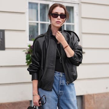 copenhagen, denmark august 05: a guest wears brown hair in a low bun, black rectangular sunglasses with dark lenses, a black leather bomber jacket, a black tank top, blue straight leg jeans, a black top handle bag, black leather pointed toe flat mules shoes, outside almada label, during copenhagen fashion week spring/summer 2027, on august 05, 2026 in copenhagen, denmark (photo by edward berthelot/getty images)