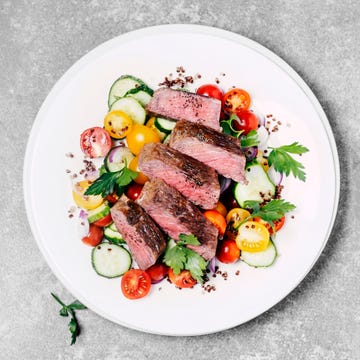 a plate of steak with fresh salad on gray background