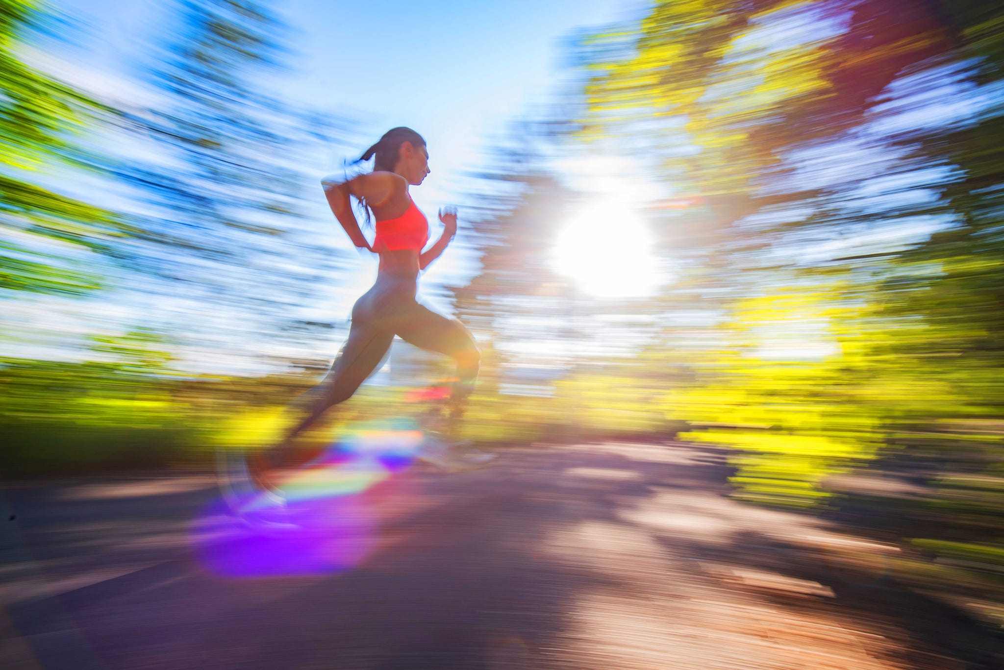 A person running briskly through a sunny, blurred landscape. A person running briskly through a sunny, blurred landscape.
