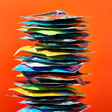 A colorful stack of various condom packages against a bright orange background. A colorful stack of various condom packages against a bright orange background.