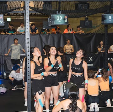 athletes in a gym competition, spectators in the background.