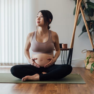 Young Asian Pregnant Woman Practising Yoga At Home beautiful young asian pregnant woman resting after doing pregnancy yoga at home. healthy and active pregnancy lifestyle concept.