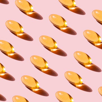 Pattern of yellow Fish Oil capsules with Omega-3 repetition on Pink Background pop art pattern made of fish oil capsules with omega 3, vitamin d on pink background studio shot. the concept of healthy eating, disease prevention and treatment. taking nutritional supplements and vitamins. biologically active additives.