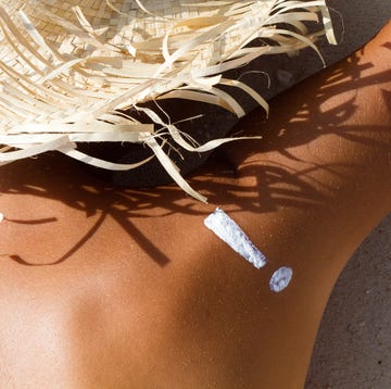Skin warning with an exclamation point on a bare back woman young woman on beach with suntan lotion