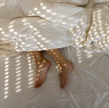 young woman sleeping in her bed, in the photo are her feet, not covered with duvet