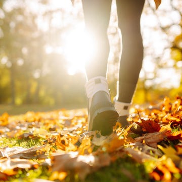 Close-up of female legs in hiking boots walks on ground with yellow-orange dry fall leaves during autumn season in park or forest. close up of female legs in hiking boots walks on ground with yellow orange dry fall leaves during autumn season in park or forest. feet walking in outdoor nature. healthy lifestyle on leisure activity