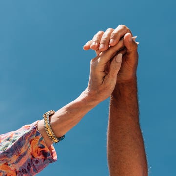 Close-Up of Senior Couple Holding Hands Under Blue Sky a heartfelt close up of two mature hands reaching up and interlocking against a vivid blue sky. the image captures the essence of connection, love, and trust between an older couple.