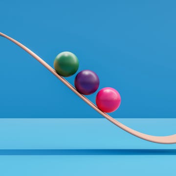 computer generated image of green purple and pink spheres rolling down orange ramp in front of blue background.