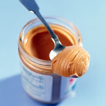 spoon with peanut butter above a jar