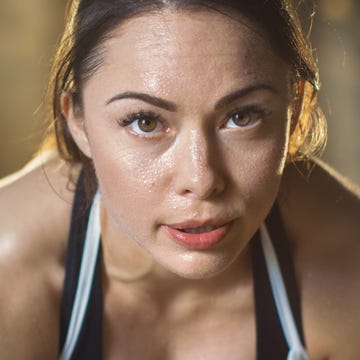 shot of a beautiful athletic brunette resting on the bench and smiling into the camera