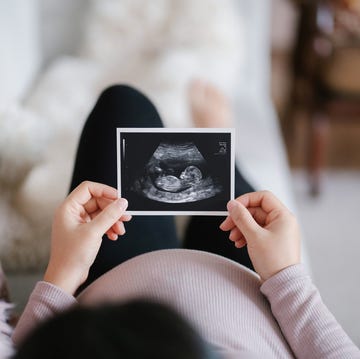Young Asian pregnant woman lying on sofa at home, looking at the ultrasound scan photo of her baby. Mother-to-be. Expecting a new life concept young asian pregnant woman lying on sofa at home, looking at the ultrasound scan photo of her baby mother to be expecting a new life concept