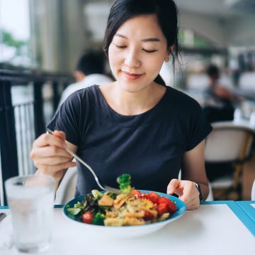 Young Asian woman enjoying a healthy meal for lunch. She is having fresh and colourful vegan salad bowl with organic greens and fruits at a vegan restaurant. Healthy eating, go green lifestyle young asian woman enjoying a healthy meal for lunch she is having fresh and colourful vegan salad bowl with organic greens and fruits at a vegan restaurant healthy eating, go green lifestyle