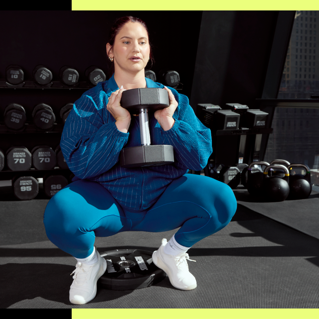 Person holding a dumbbell in a gym squat position.