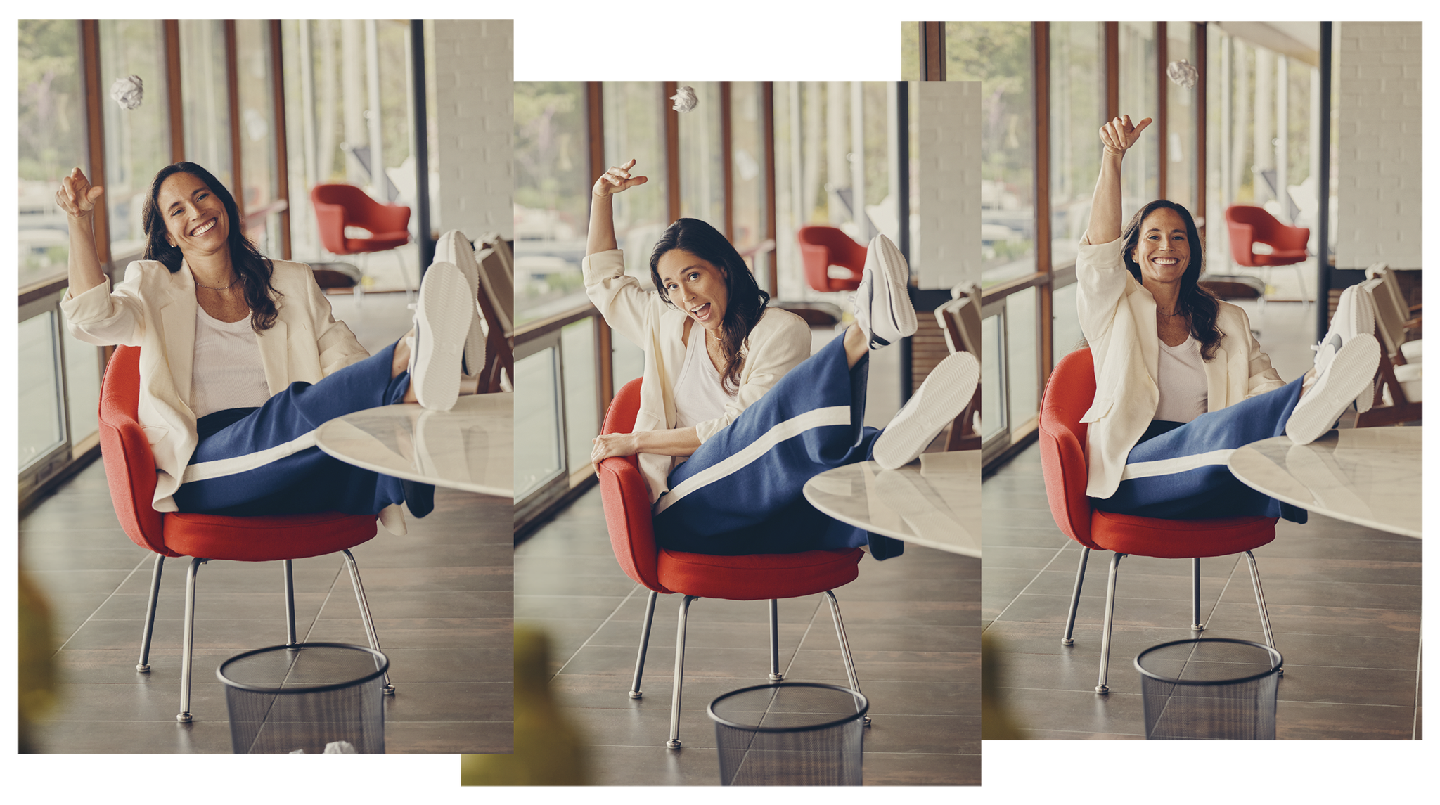 Person in red chair playfully tossing crumpled paper towards a waste bin in a bright room.