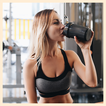 Vanilla nutrition shake with a glass on a countertop and a woman drinking from a shaker in a gym setting. Vanilla nutrition shake with a glass on a countertop and a woman drinking from a shaker in a gym setting.