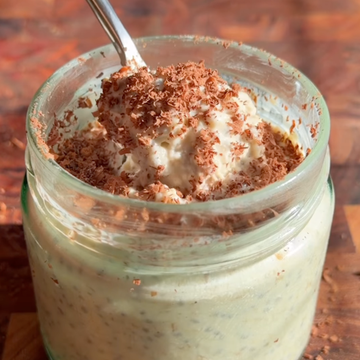 jar of creamy overnight oats topped with grated chocolate and a spoon.