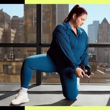 Person doing lunges with dumbbells in a gym overlooking cityscape.