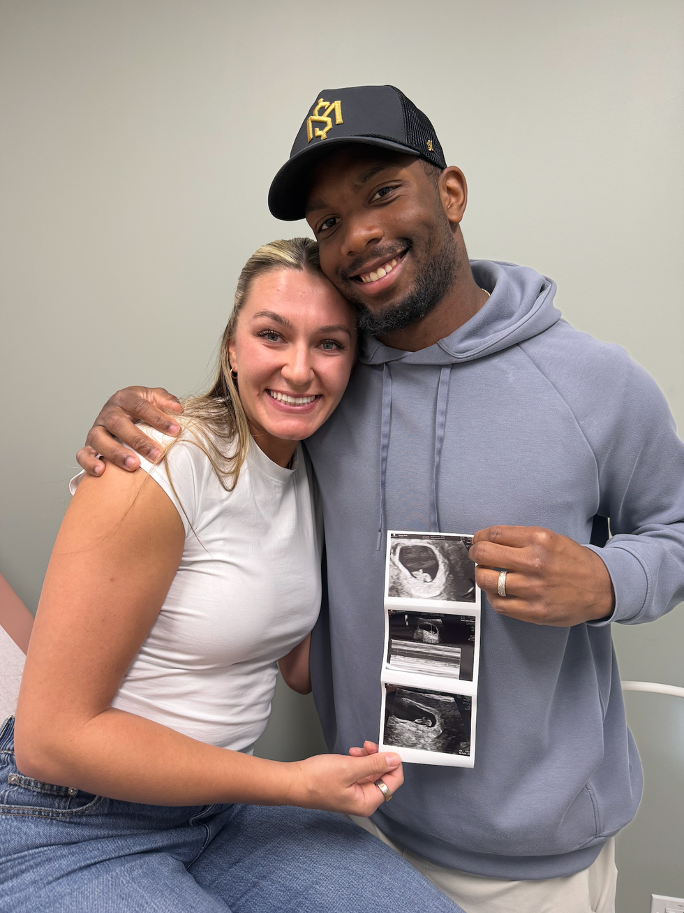 Couple smiling and holding ultrasound photos in a medical setting. Couple smiling and holding ultrasound photos in a medical setting.