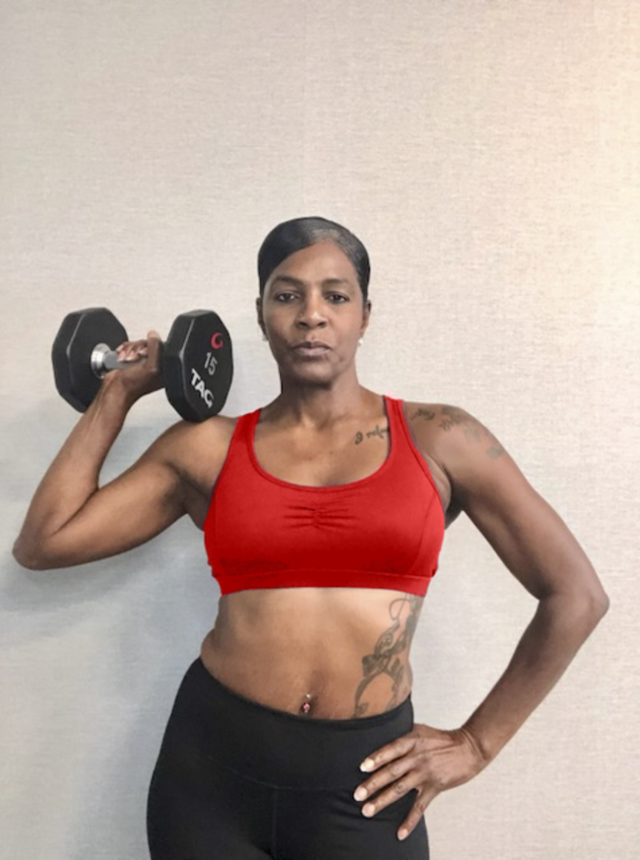 Person in a red sports bra holding a dumbbell with a neutral expression, showcasing strength and fitness. Person in a red sports bra holding a dumbbell with a neutral expression, showcasing strength and fitness.
